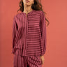 Woman wearing a maroon and pink striped outfit against a red background