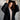 Woman wearing a black coat over a beige outfit against a neutral background