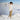 Woman in a white lace sweater and beige pants standing on a snowy mountain
