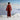 Woman in a red top and brown pants standing on a snowy mountain
